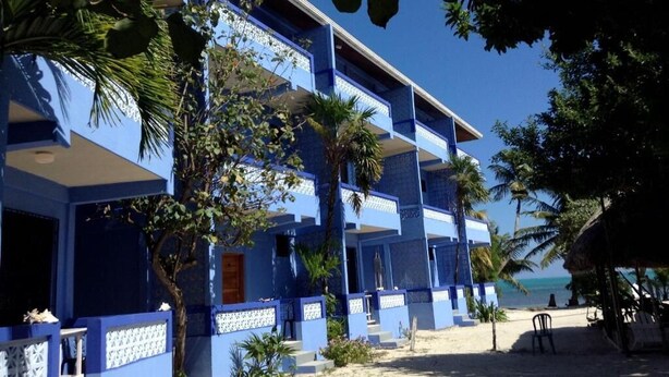 Ein mehrstöckiges Hotel mit blauer Fassade, Balkonen und Blick auf den Strand.