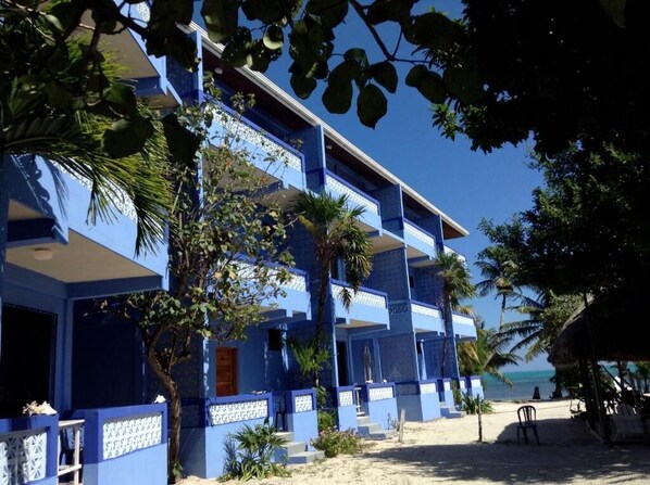 A multi-story hotel with blue exteriors, balconies, and a beach view. - Anchorage Beach Resort (Caye Caulker)