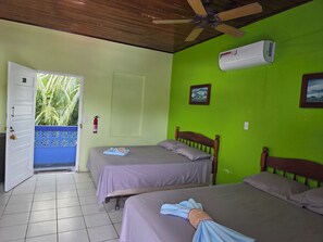 A room with two beds, a ceiling fan, an air conditioning unit, and a door leading outside. - Anchorage Beach Resort (Caye Caulker)