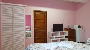 Un dormitorio con cama, armario, televisor y refrigerador.