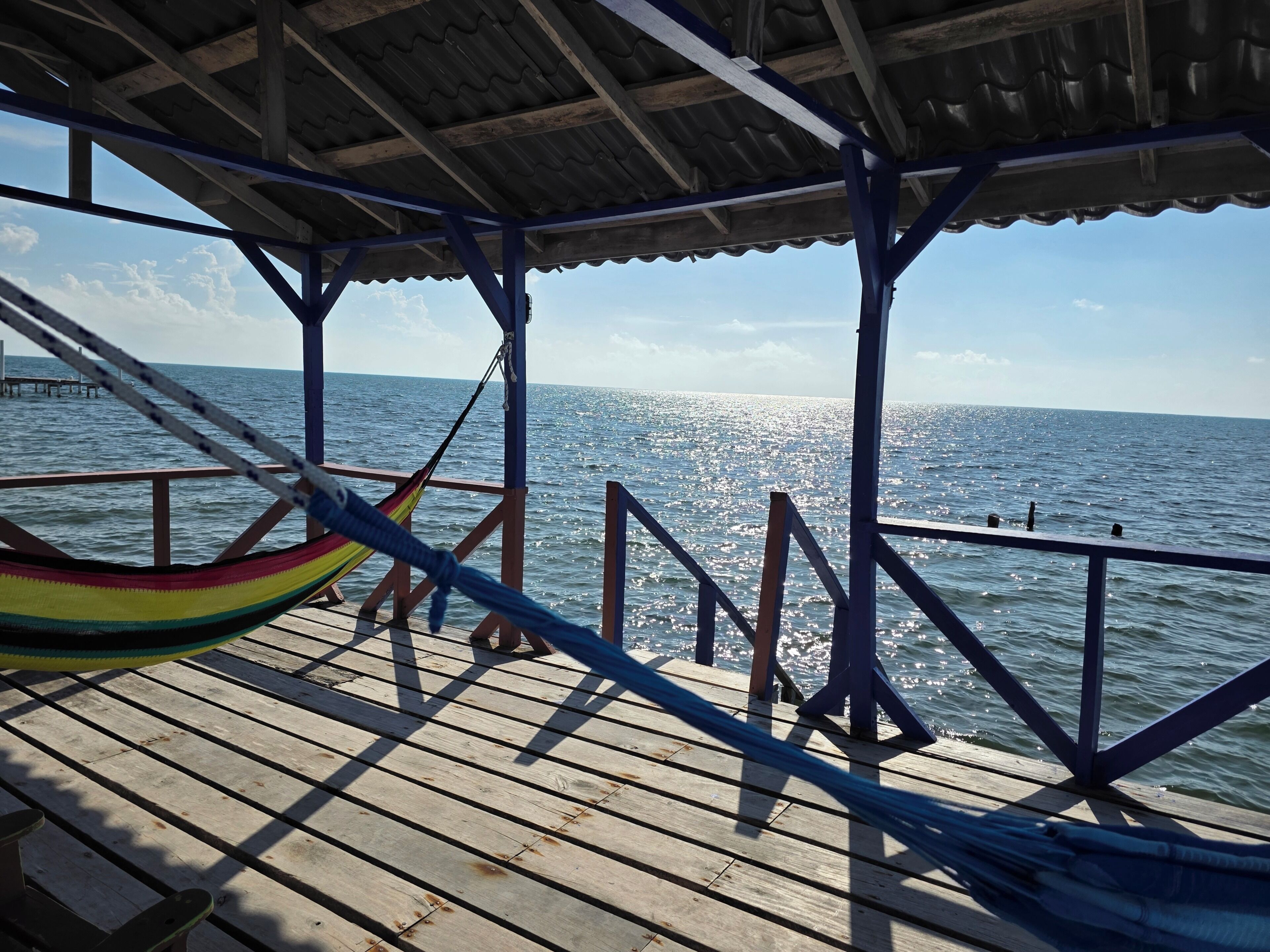 Une terrasse en bois avec un hamac et une balustrade donnant sur une étendue d’eau.