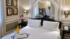 A hotel room with a large bed, a mirror, framed pictures on the wall, and a tray with glasses and a candle. - Hotel Santo Stefano (Venice)