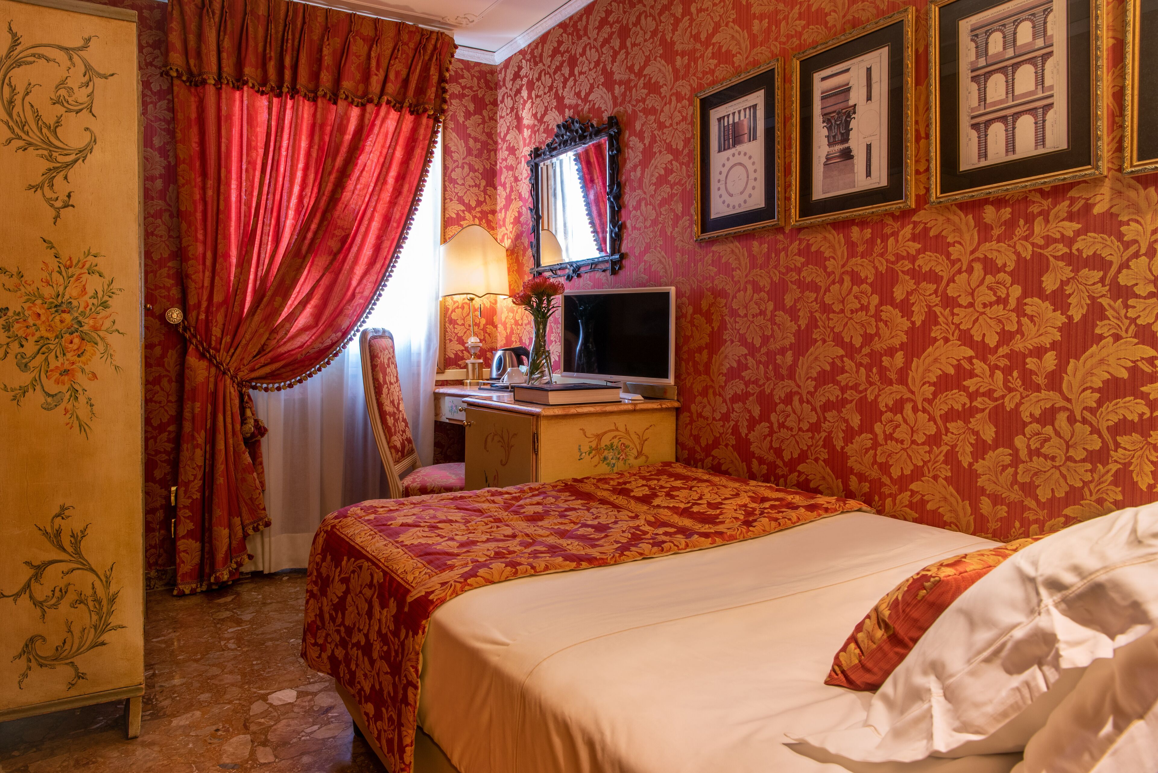 Una habitación de hotel con cama, escritorio, silla, televisor y espejo.