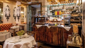 A restaurant with a wooden bar, white tablecloths, and a variety of food and drink options. - Hotel Santo Stefano (Venice)