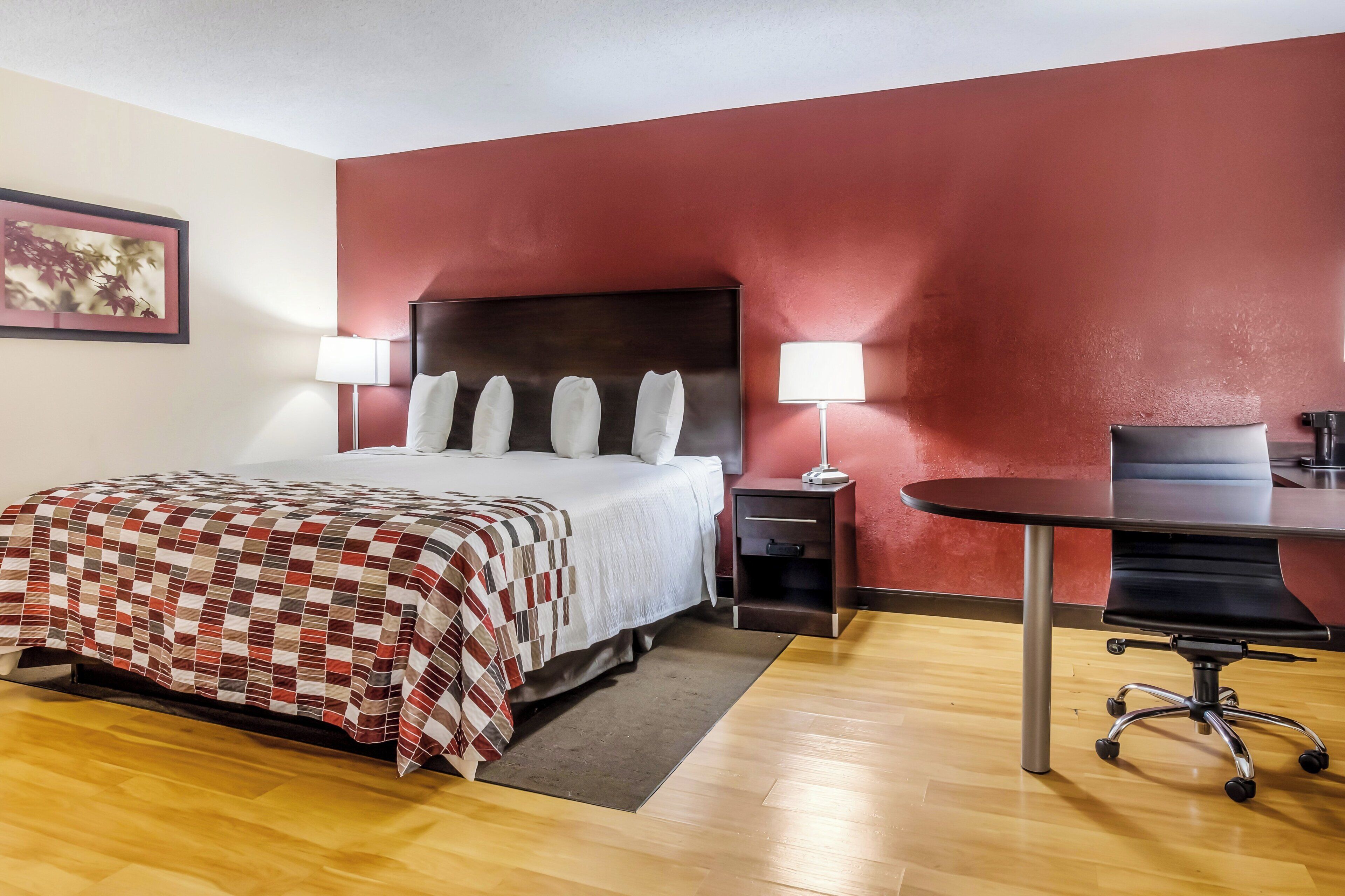A hotel room with a bed, bedside tables, a desk, and a chair.