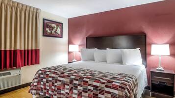 Habitación de hotel con una cama grande, dos lámparas de noche, una mesita de noche y un aire acondicionado instalado en la pared.