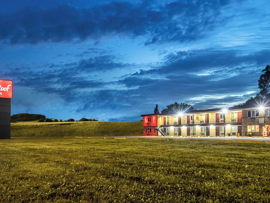 Un RedRoof Inn con un edificio de dos pisos, un estacionamiento y un campo de césped.