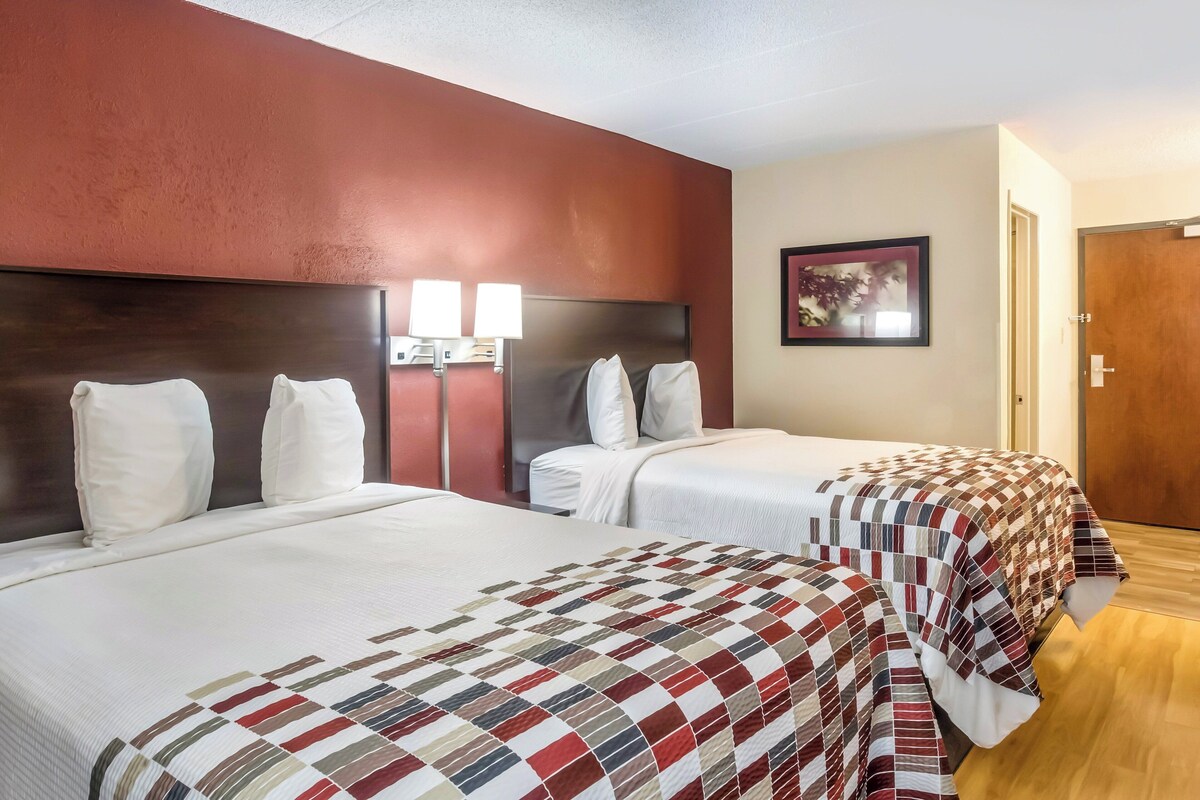 Two beds with headboards, a wall-mounted lamp, and a framed picture.
