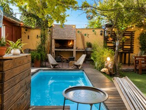 A backyard with a swimming pool, a wooden deck, and a brick fireplace. - Estacion Mendoza Hostel (Mendoza)