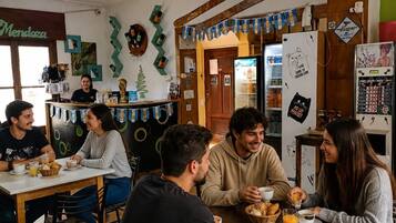 A café with wooden furniture, a refrigerator, and a wall decorated with flags and a mural.