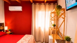 A room with a bed, a desk, a chair, a TV, and a window with curtains. - Estacion Mendoza Hostel (Mendoza)