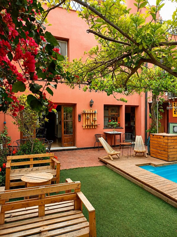 A backyard with a swimming pool, wooden deck, and outdoor seating area. - Estacion Mendoza Hostel (Mendoza)
