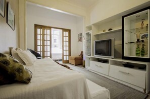 Une chambre d’hôtel avec un lit, une télévision, un canapé et une vitrine.