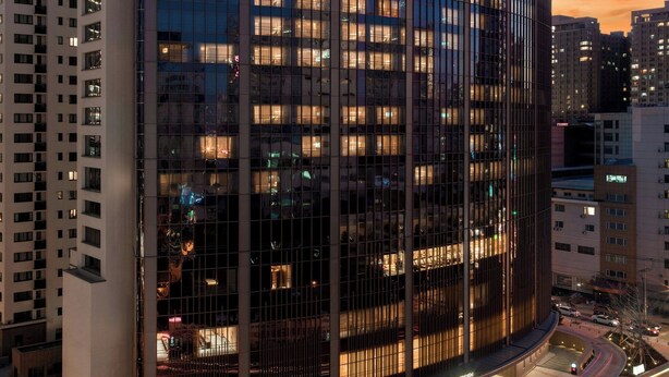 Un hôtel moderne à la façade incurvée, doté de plusieurs étages et d’une entrée imposante.