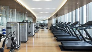 Une salle de sport équipée de machines de cardio, d’appareils de musculation et de tapis de course.