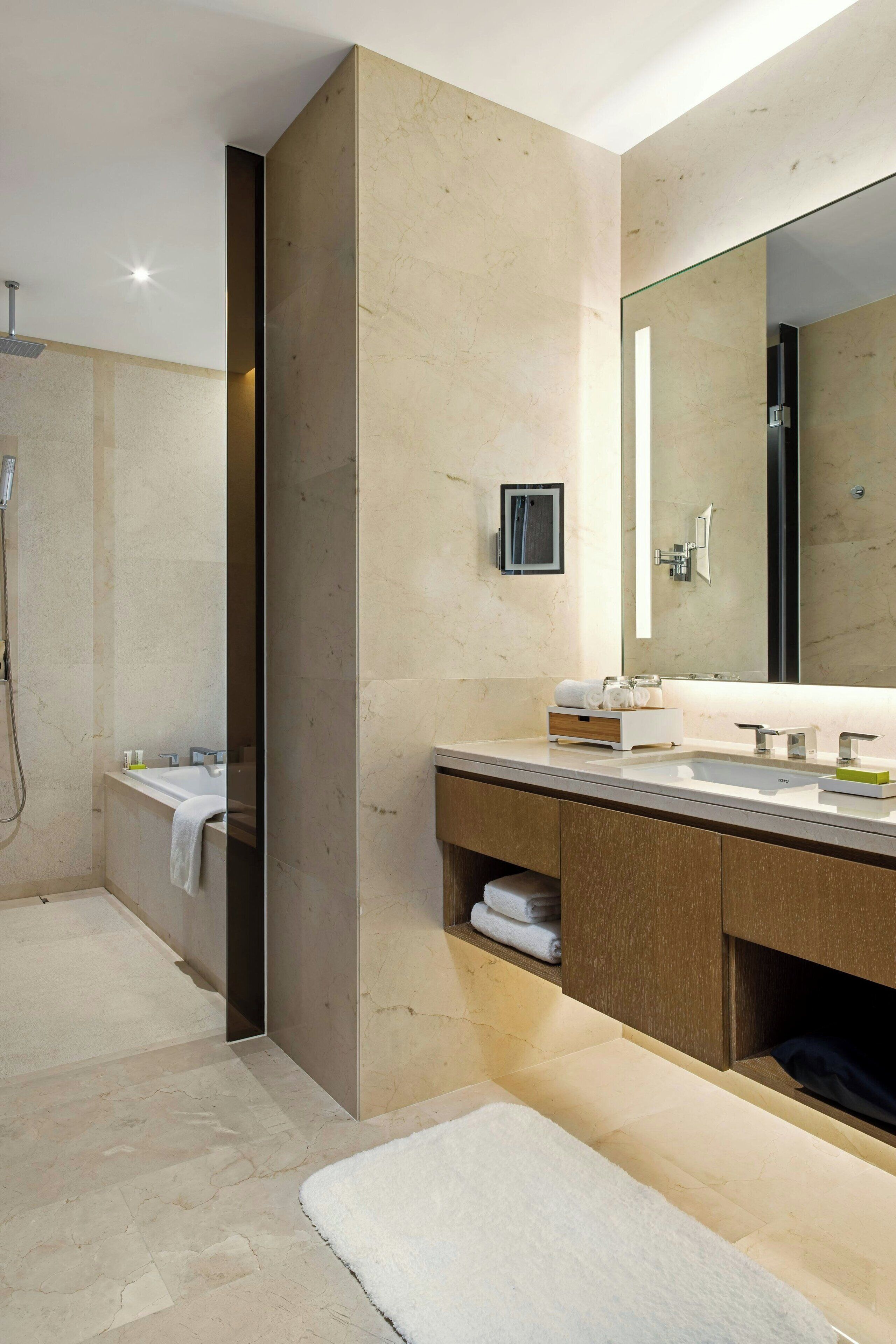 Un baño moderno con un espejo grande, una bañera y una ducha.