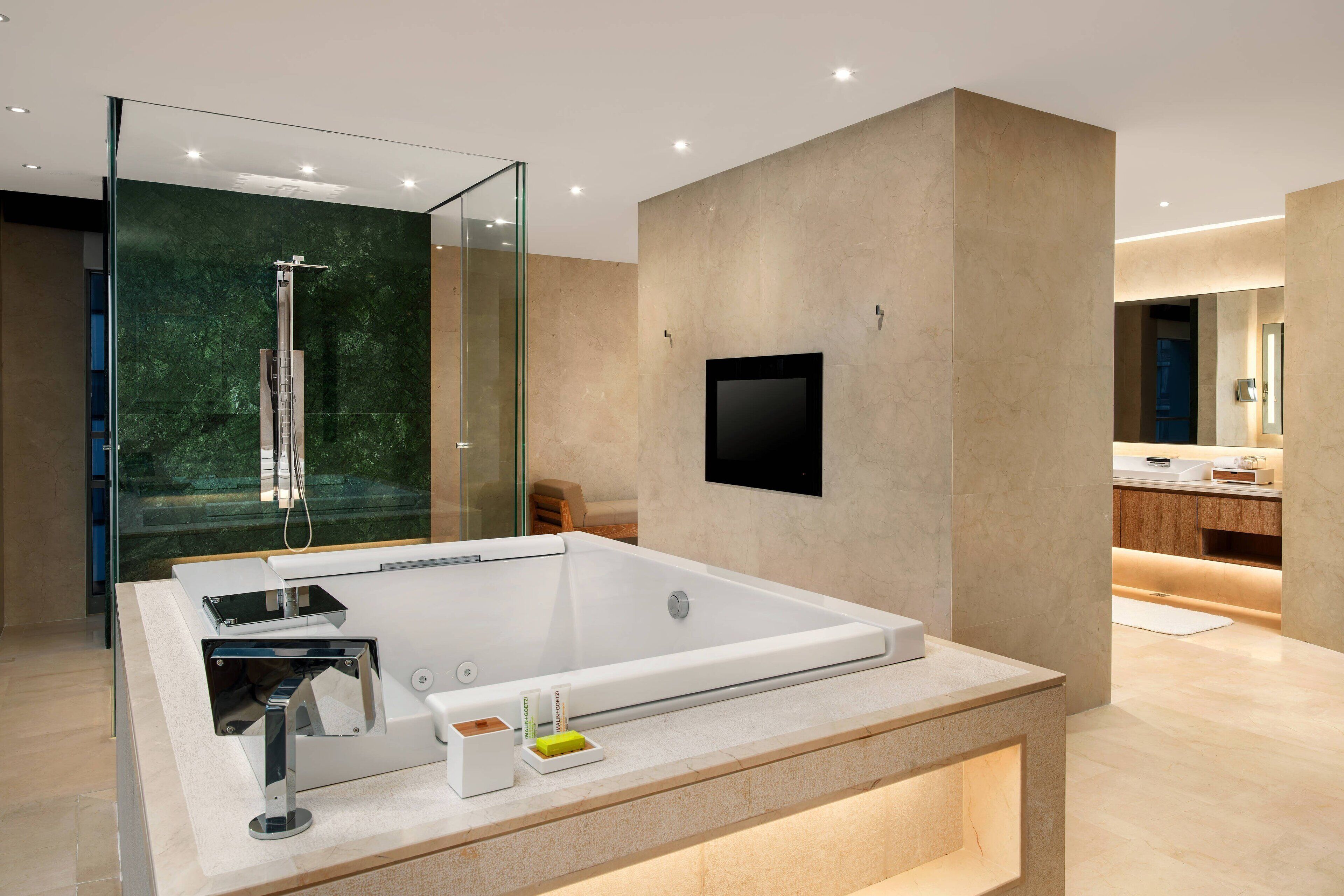 A modern bathroom with a large bathtub, a glass-enclosed shower, and a minimalist design.