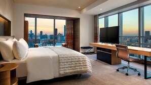 Une chambre d’hôtel avec un grand lit, un bureau et une télévision.