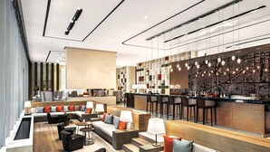 Un hall d’hôtel moderne doté d’un bar, d’espaces aménagés pour s’asseoir et d’un mur décoratif.