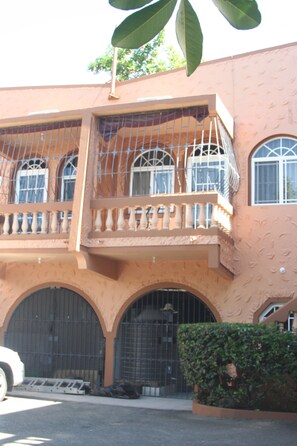 Ein Gebäude mit Balkon, Rundbogenfenstern und einem Eingangstor.