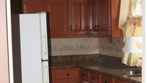 A kitchen with wooden cabinets, a white refrigerator, and a granite countertop. - Cozy Apartments (Kingston)