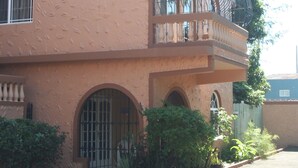 A building with a terracotta facade, a balcony with a wrought iron railing, and a gated entrance. - Cozy Apartments (Kingston)