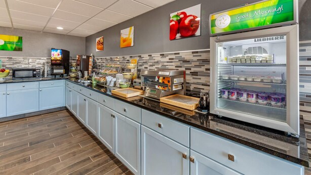 A modern kitchen area with a coffee station, a refrigerator with dairy products, and a microwave. - Quality Inn New London (New London)