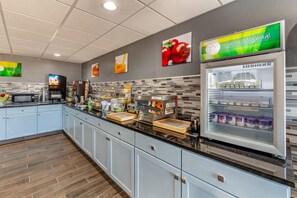 A modern kitchen area with a coffee station, a refrigerator with dairy products, and a microwave.