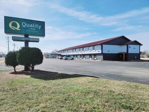 Ein Quality Inn by Choice Hotels mit Parkplatz, überdachter Parkzone und einem Gebäude mit rotem Dach.
