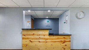 A reception desk with a wooden finish and a sign above it. - Quality Inn New London (New London)
