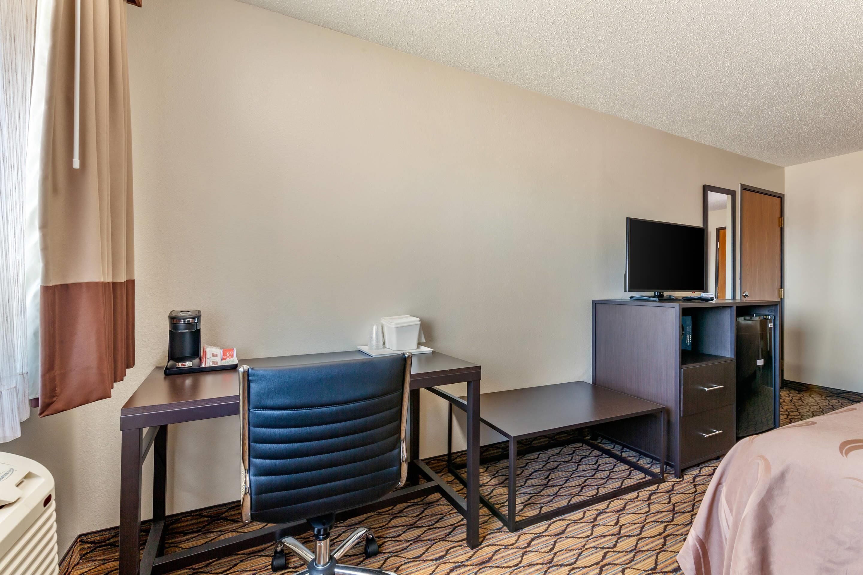 Une chambre d’hôtel équipée d’un bureau, d’une chaise, d’une télévision et d’un lit.