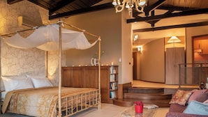 Un lit à baldaquin, une bibliothèque en bois et un escalier menant à un balcon.