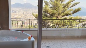 Une salle de bain avec une baignoire, une vue sur la ville et un balcon avec une balustrade.