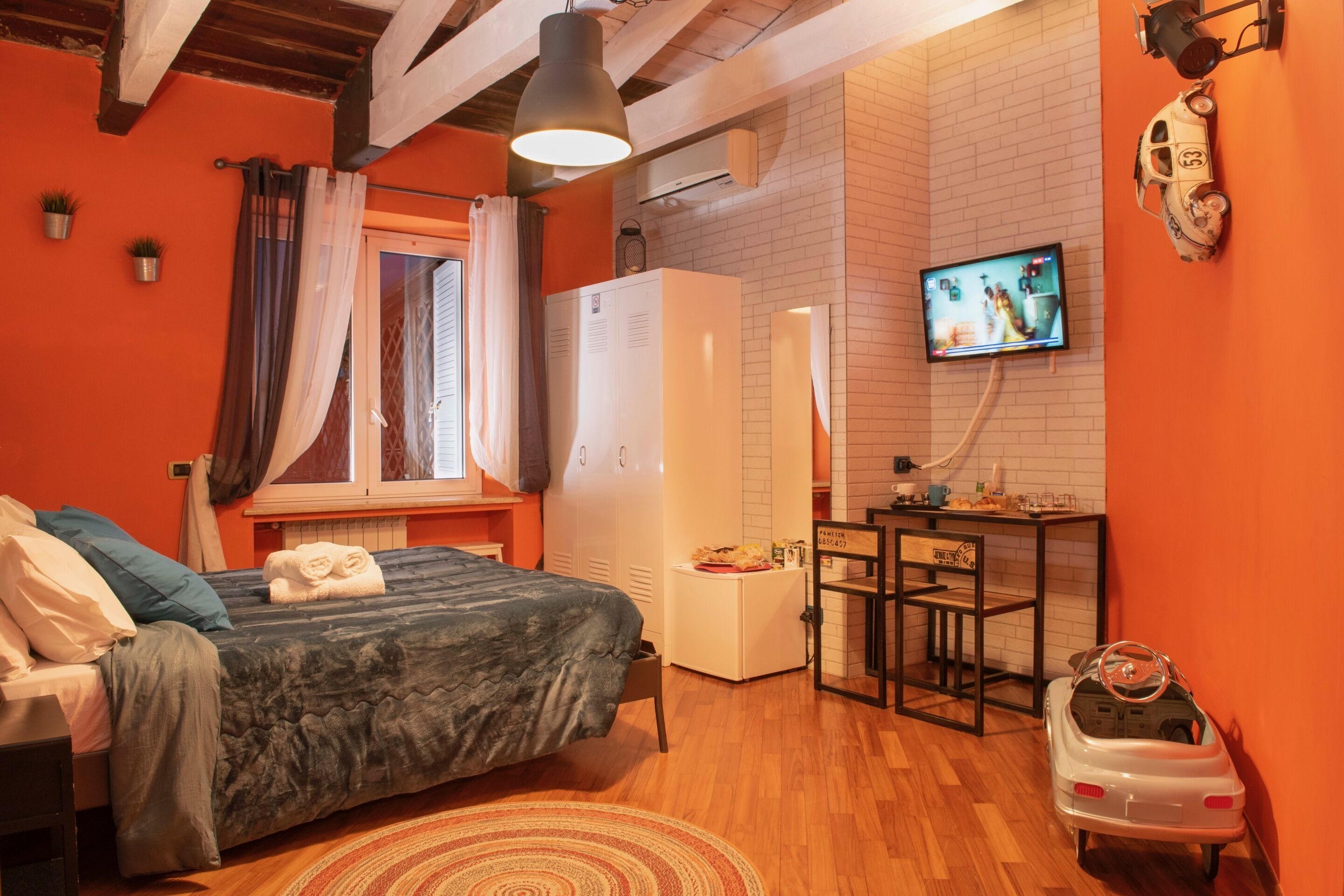 A bedroom with a bed, a desk, a television, and a toy car.