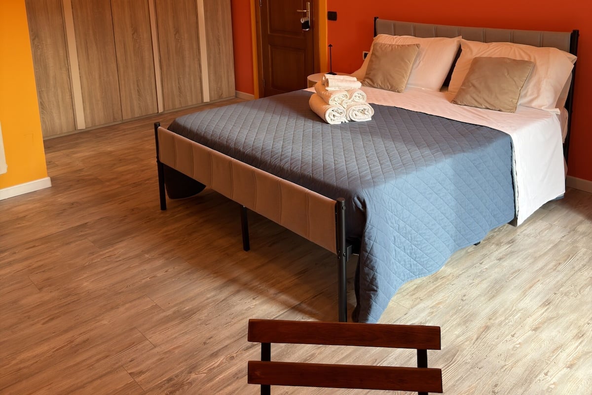 Une chambre à coucher avec un lit, un plancher en bois et un banc.