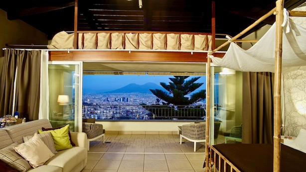 Un balcon avec vue sur la ville, un canapé, un fauteuil et un lit.