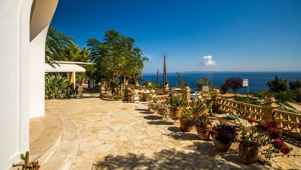 A stone-paved patio with potted plants and a view of the sea. - Blue Horizon Studios (Zakynthos)