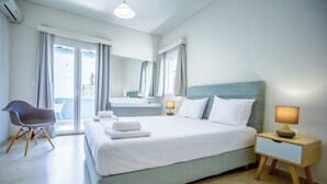 A modern hotel room with a large bed, a bedside table with a lamp, a chair, and a balcony with curtains. - Blue Horizon Studios (Zakynthos)