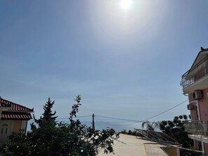 A residential street with buildings, a clear sky, and a distant view of the sea. - Blue Horizon Studios (Zakynthos)