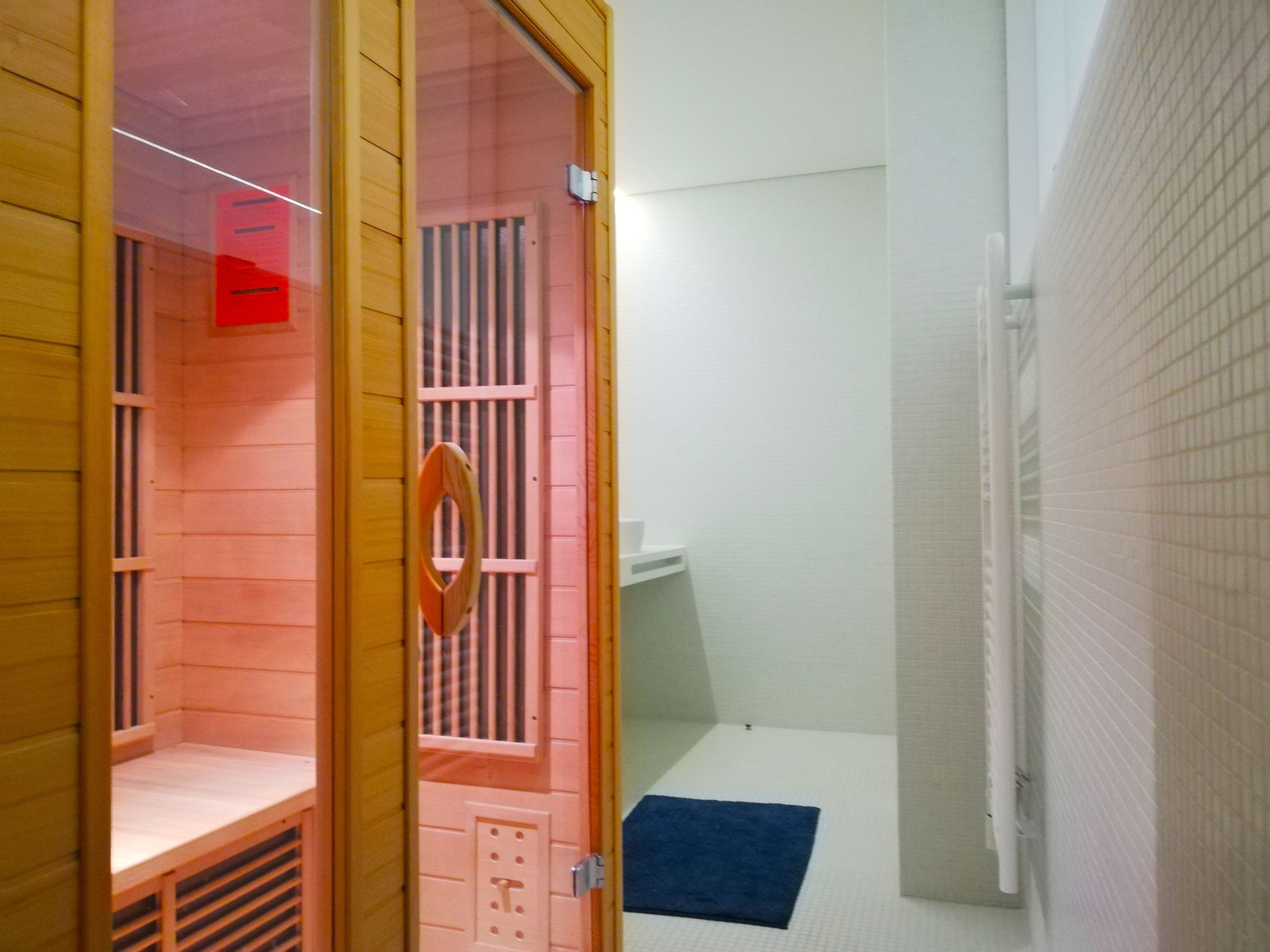 Een houten sauna met een bankje, een klein raam en een deur met een handvat.