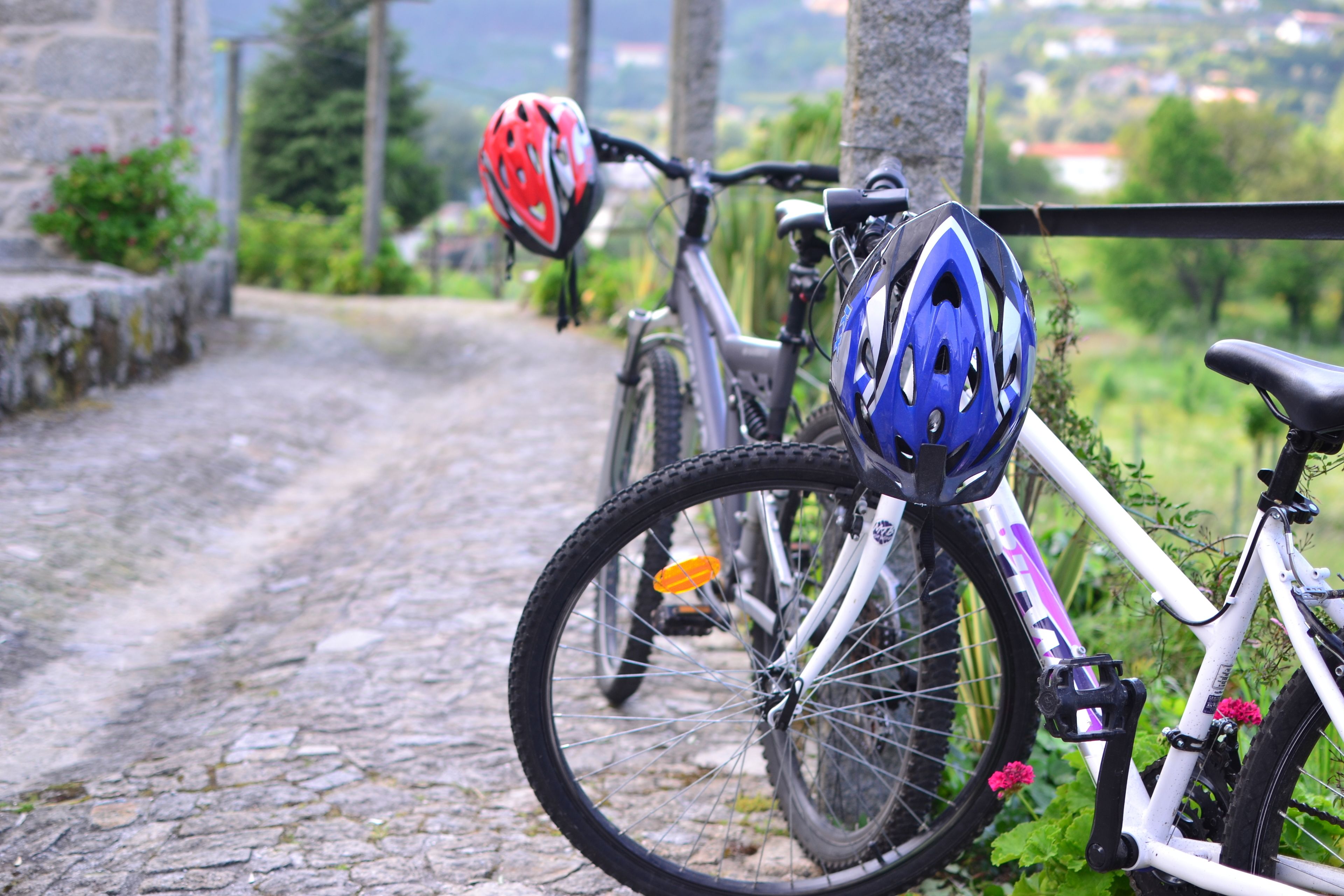 Un vélo avec un casque bleu et des pédales orange, garé sur un chemin pavé.