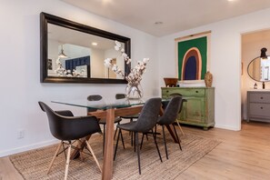 A dining area with a glass table, four chairs, a vase with flowers, a mirror, and a green cabinet. - Crestview B44 (Mammoth Lakes)