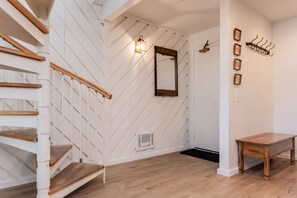 A staircase with wooden steps and handrails, a wall-mounted mirror, a small table, and a wall-mounted heater. - Crestview B44 (Mammoth Lakes)