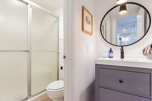 A bathroom with a glass shower enclosure, a white toilet, a sink with a mirror, and a framed picture on the wall. - Crestview B44 (Mammoth Lakes)