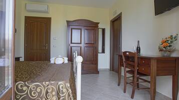 A bedroom with a bed, a wooden wardrobe, a desk, and a chair.