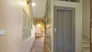 Un couloir avec une arche en pierre, une porte portant une inscription et un escalier.