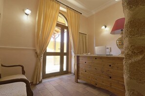 A room with a wooden dresser, a chair, and a door with curtains.