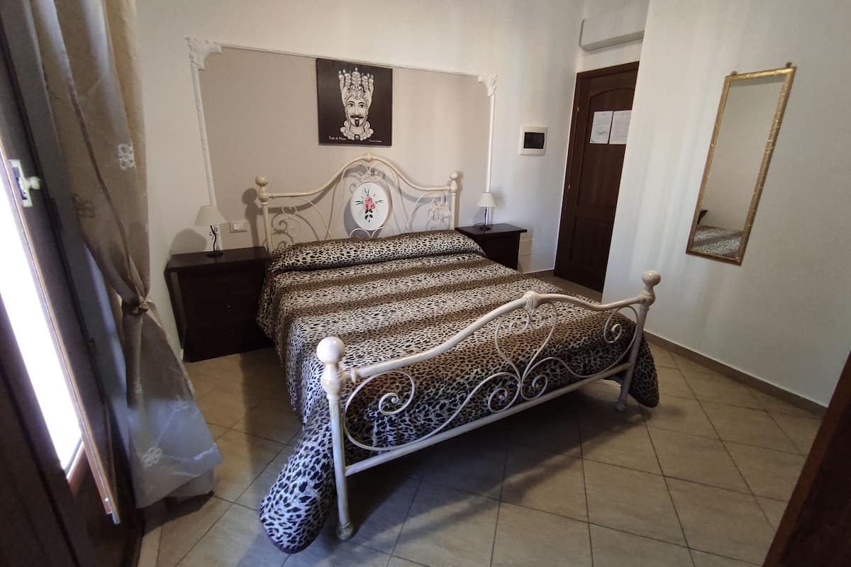 Una camera da letto con un letto, un comodino, uno specchio e una porta.