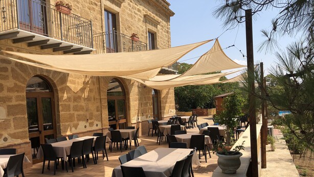 Une terrasse extérieure avec des murs en pierre, des tables et des chaises.