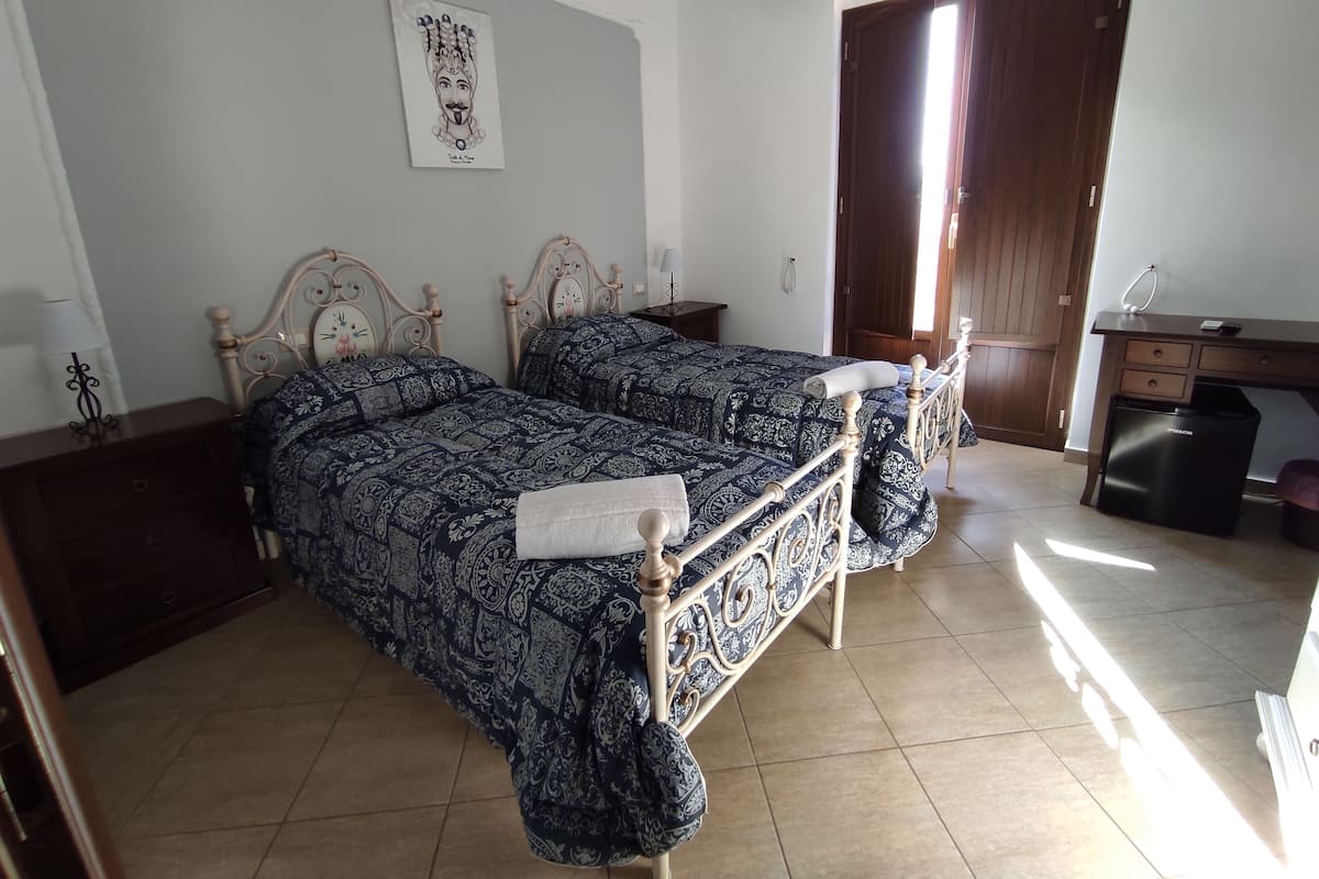 Camera da letto con due letti, una scrivania e un cestino.
